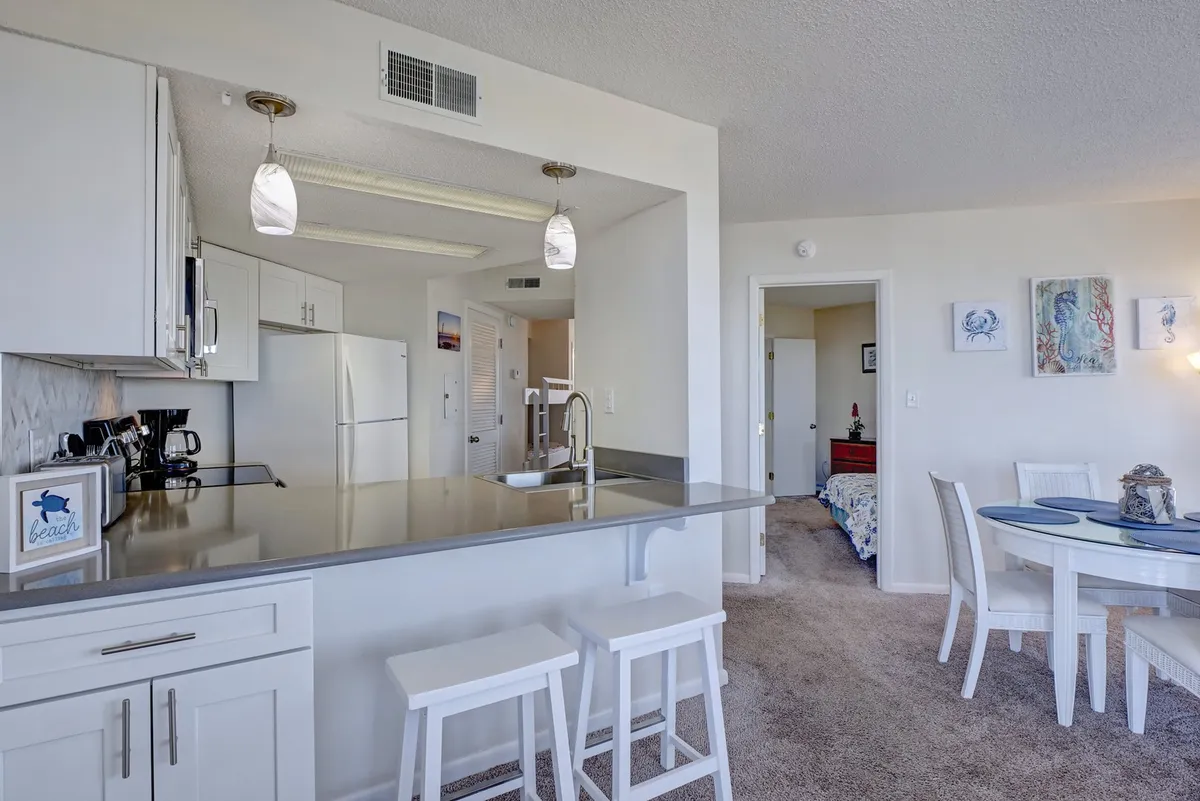 A welcoming open-plan area displaying both a kitchen island and a dining table, surrounded by decorative wall art. The space is set for cooking, entertaining, and enjoying casual dining, with an emphasis on togetherness and flow between kitchen and dining areas.