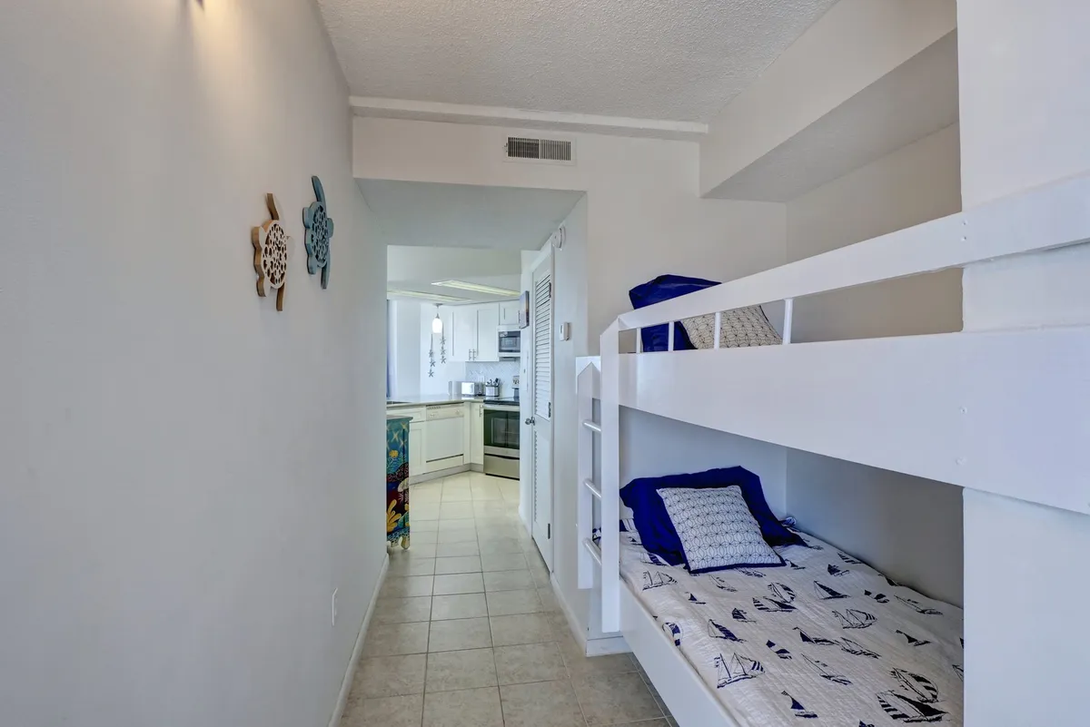 A hallway nook with twin bunk beds is visible, enhanced by playful, sea-themed wall art and a view into the nearby kitchen, suggesting a vibrant, family-friendly space.