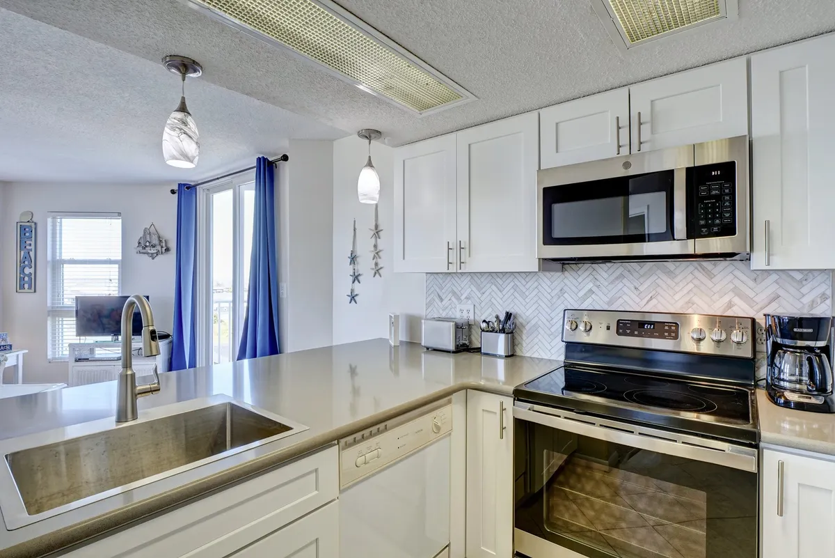 An inviting kitchen island with stainless steel appliances and a cheerful herringbone backsplash, complemented by brightly colored curtains that let in plenty of natural light. The scene suggests a lively and social environment ideal for preparing and sharing meals.