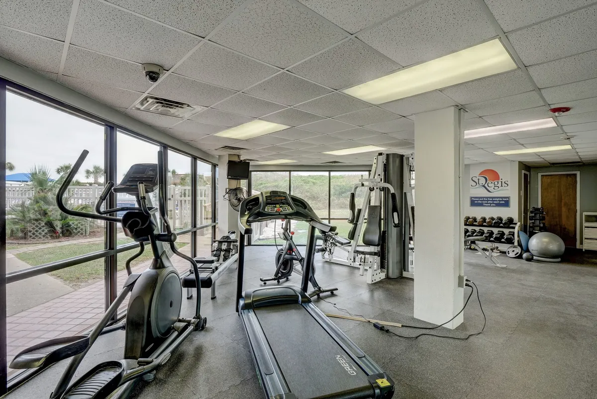 A bright and motivating fitness center with modern treadmills, elliptical machines, weightlifting equipment, and large windows providing plenty of natural light and inviting views. The space welcomes both solo workouts and group fitness events.